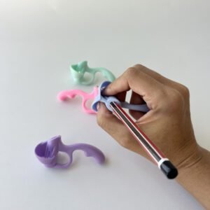 A hand demonstrating the use of a light blue 5-finger pencil grip corrector on a pencil, with other pastel pencil grips blurred in the background.