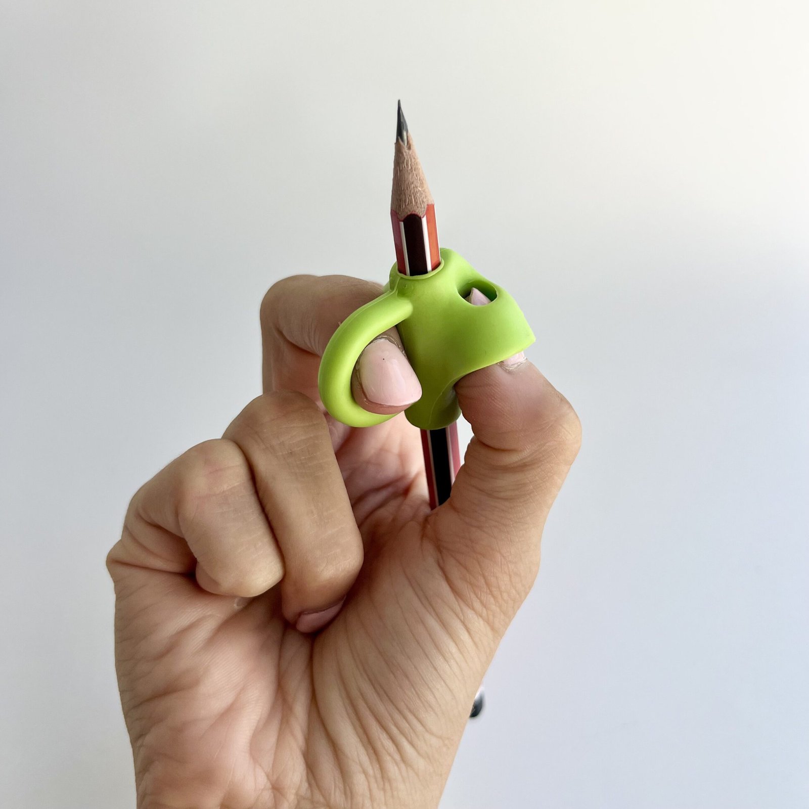 person-using-green-3-finger-pencil-grip Close-up of a hand demonstrating the proper tripod grip on a pencil using a green 3-finger positioning pencil grip.