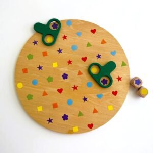 wooden-shape-and-colour-matching-game-board Overhead view of the I Spy Colour and Shape Matching Game. A circular wooden board is covered with small, colourful geometric shapes and flowers. Two green magnifier tools rest on the board, and two wooden dice are to the side.