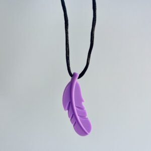 A single purple chewable necklace shaped like a feather, hanging on a black cord against a light grey background.