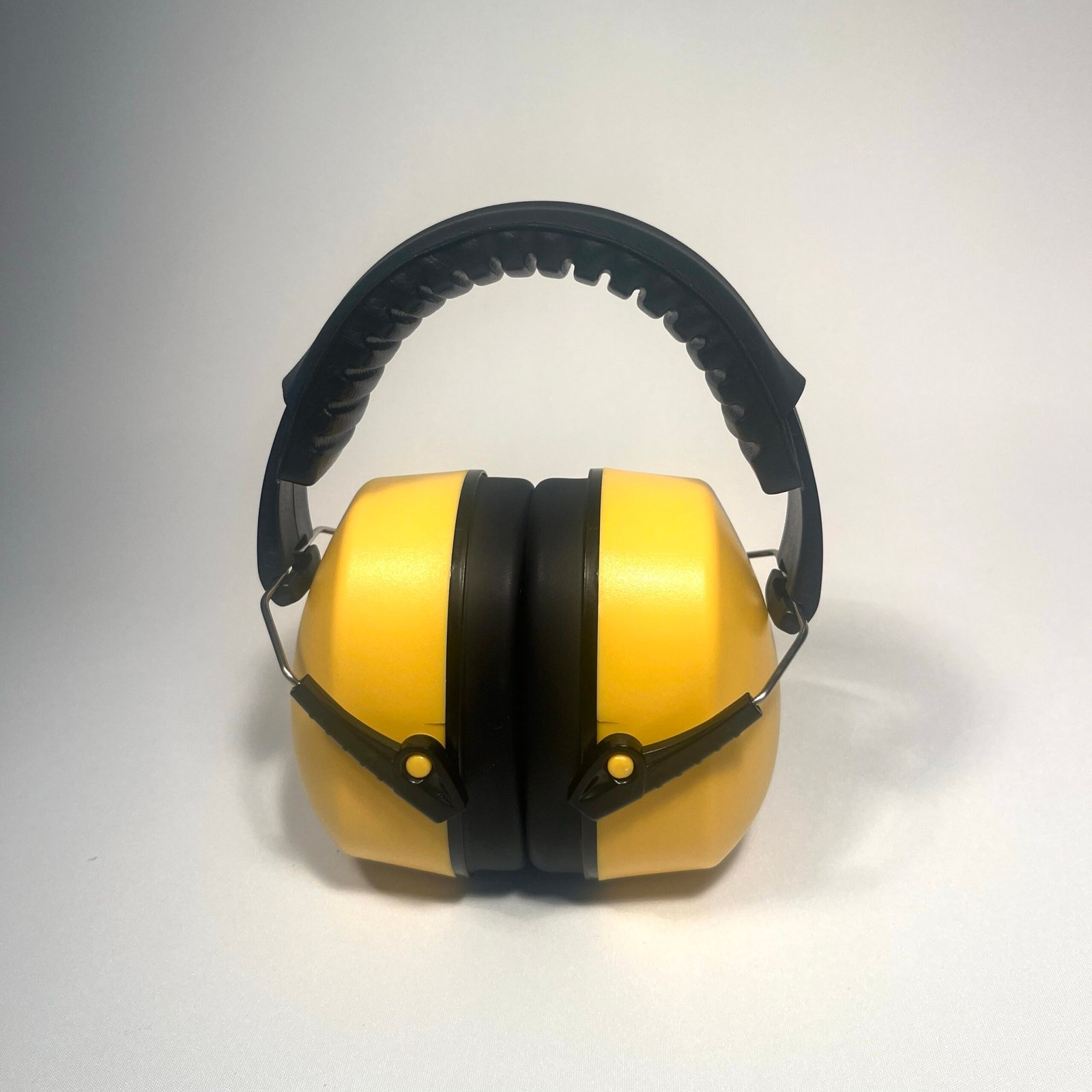 Front view of a single bright yellow noise cancelling headphone for kids, featuring a black padded headband and earcups, designed for hearing protection.