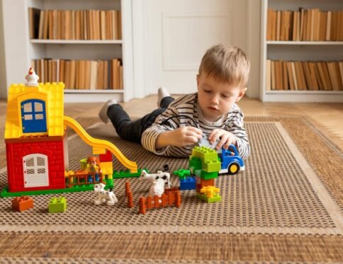 Young boy engaged in imaginative block play on a carpeted floor indoors.