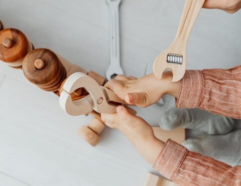 Close-up of a child playing with wooden toy tools, enhancing creativity and motor skills.